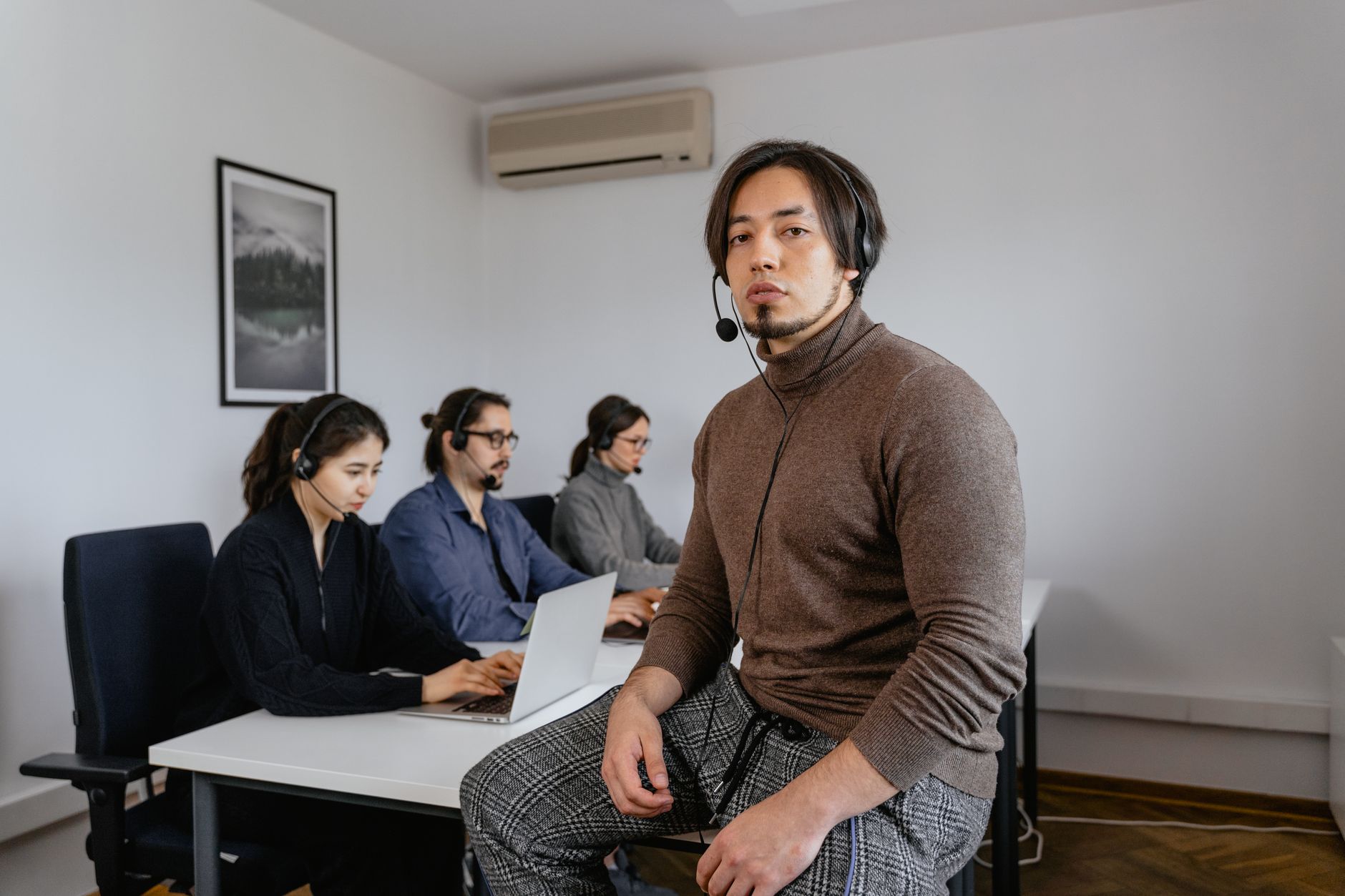 Call center team leader coaching an agent at a workstation with headsets during a performance review.
