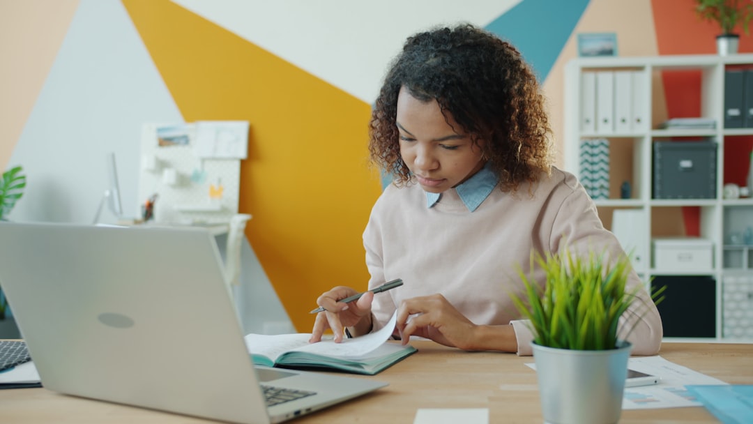 Business owner calculating customer acquisition cost and marketing ROI with a calculator and notebook.