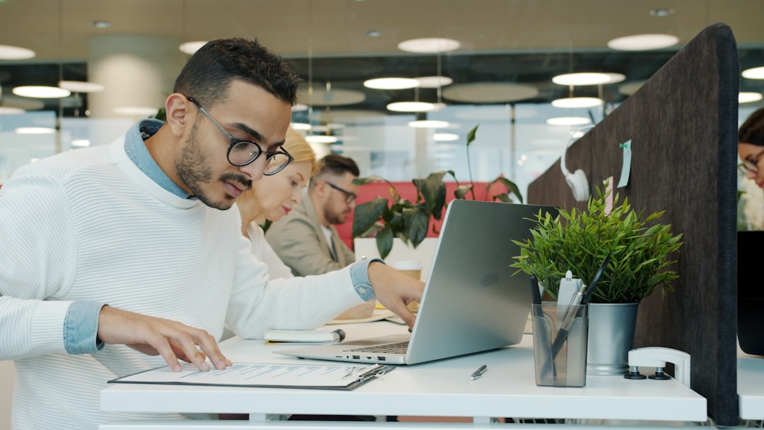 Marketing professional reviewing lead generation analytics and cost metrics in a spreadsheet on a laptop.