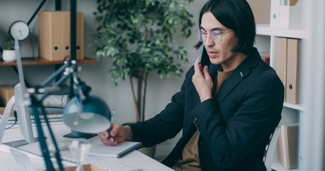 Sales agent at a desk reviewing call script notes while wearing a phone headset for outbound appointment setting calls.